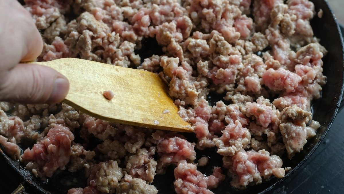 espatula raspando en la sarten la carne picada previamente congelada